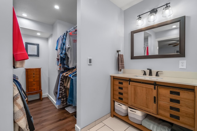 bathroom with recessed lighting, baseboards, wood finished floors, and vanity