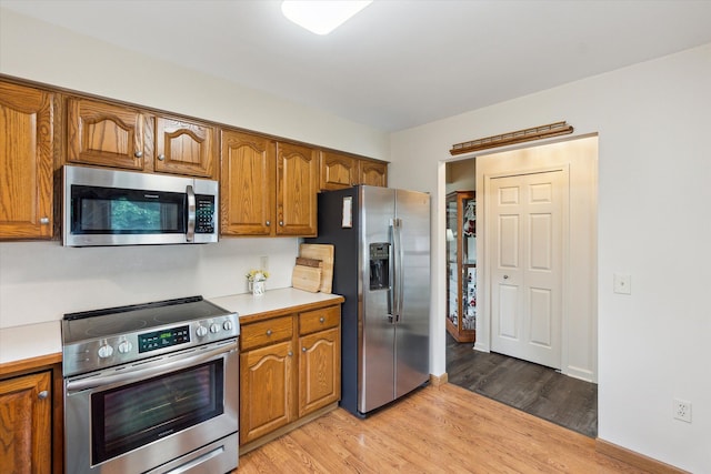 kitchen featuring light countertops, brown cabinets, light wood finished floors, and stainless steel appliances