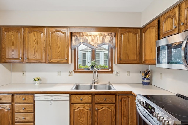 kitchen with brown cabinetry, stainless steel appliances, light countertops, and a sink