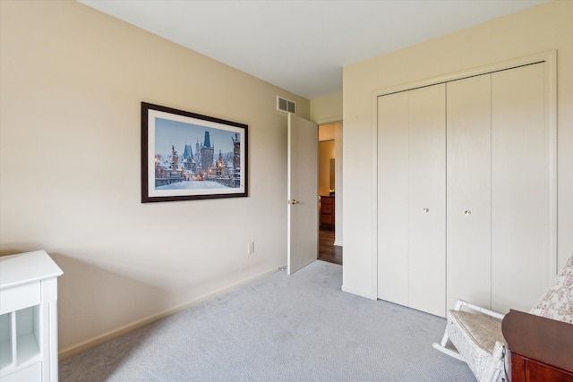 unfurnished bedroom with light carpet, visible vents, baseboards, and a closet