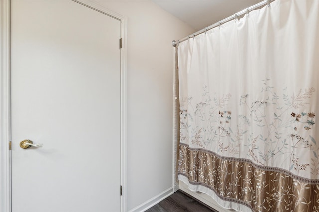 full bathroom featuring baseboards, a shower with curtain, and wood finished floors