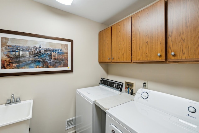 clothes washing area with visible vents, cabinet space, independent washer and dryer, and a sink