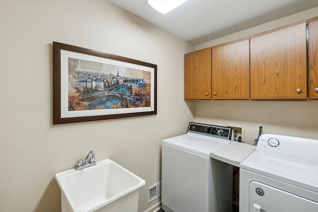 clothes washing area featuring cabinet space, visible vents, washing machine and dryer, and a sink