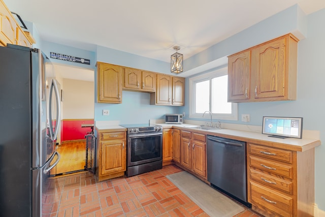 kitchen with appliances with stainless steel finishes, light countertops, brick floor, and a sink