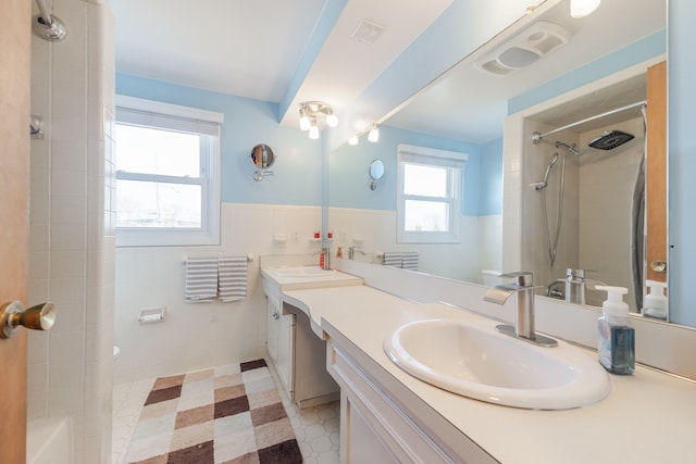 bathroom with tile walls, a shower, a wainscoted wall, and tile patterned floors