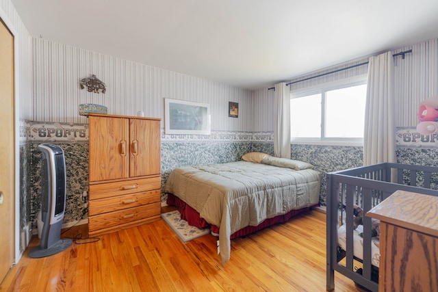 bedroom with wallpapered walls and wood finished floors