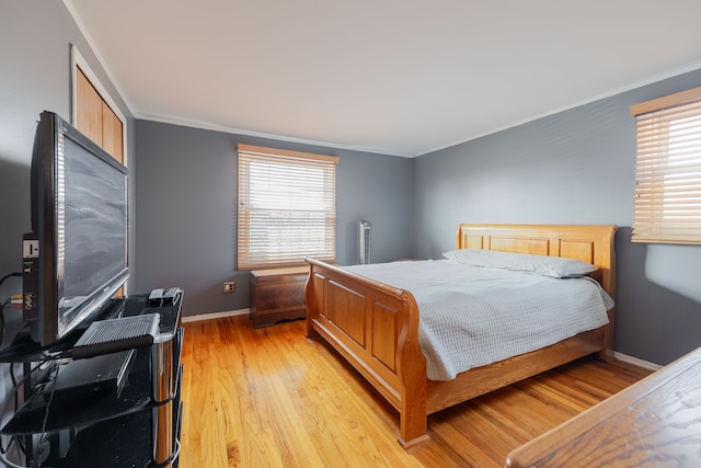 bedroom featuring light wood-style flooring, baseboards, and ornamental molding