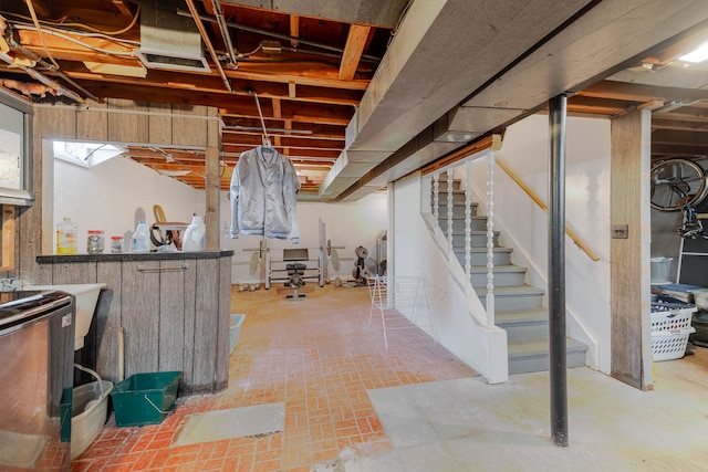 unfinished basement featuring washer / clothes dryer, stairs, and brick floor