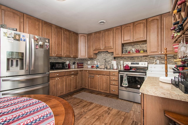 kitchen with visible vents, decorative backsplash, wood finished floors, stainless steel appliances, and a sink