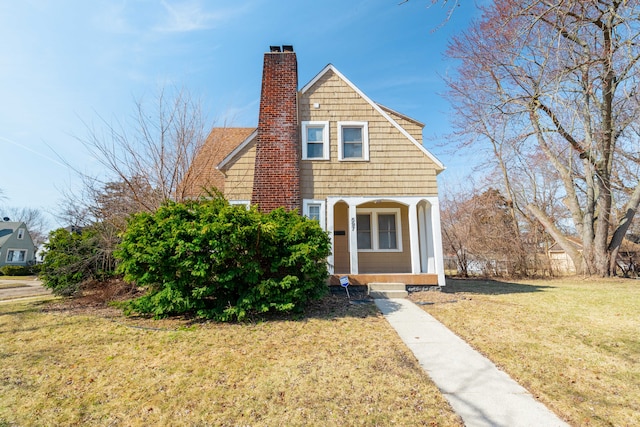 view of front of home with a front yard, a porch, and a chimney