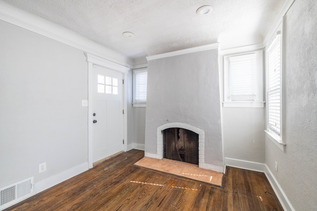 unfurnished living room featuring visible vents, a brick fireplace, baseboards, hardwood / wood-style floors, and a textured ceiling