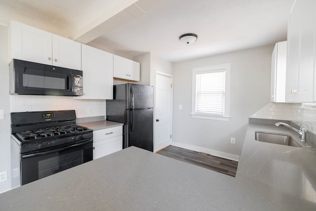 kitchen featuring baseboards, a sink, black appliances, white cabinets, and tasteful backsplash