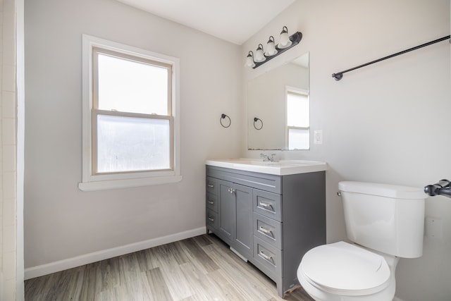 bathroom with vanity, toilet, wood finished floors, and baseboards