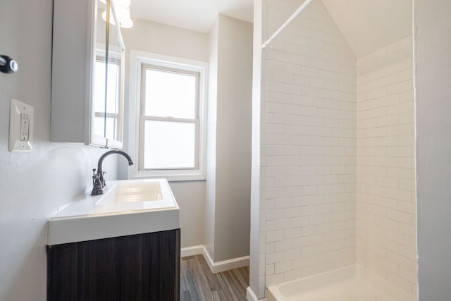 full bath featuring a shower stall, vanity, baseboards, and wood finished floors