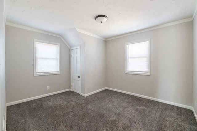 empty room with ornamental molding, baseboards, and dark colored carpet