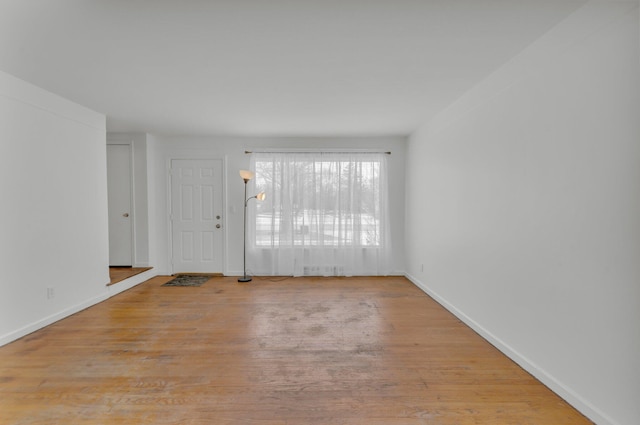 spare room featuring visible vents, baseboards, and wood finished floors