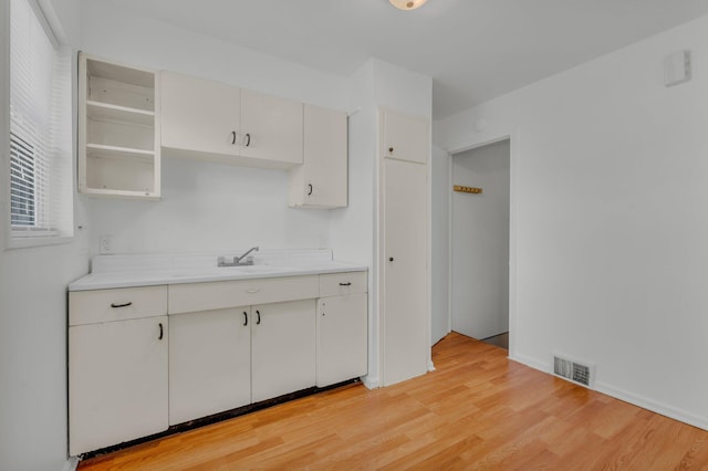 kitchen featuring a sink, visible vents, light wood-type flooring, and light countertops