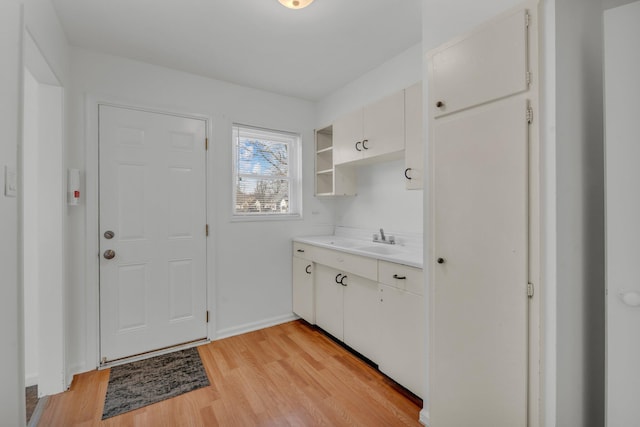 laundry room featuring light wood-style floors, baseboards, and a sink