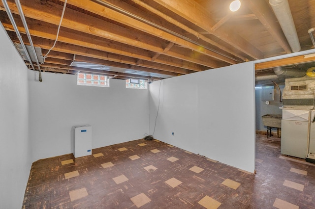 basement featuring tile patterned floors, visible vents, and electric panel