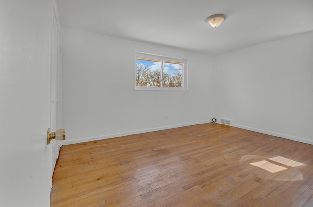 empty room featuring light wood-style floors, visible vents, and baseboards