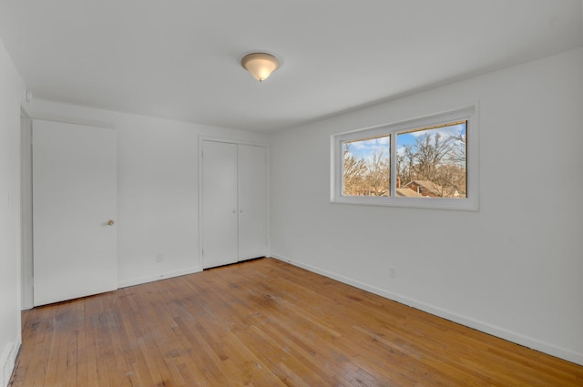 unfurnished bedroom featuring a closet, baseboards, and hardwood / wood-style flooring