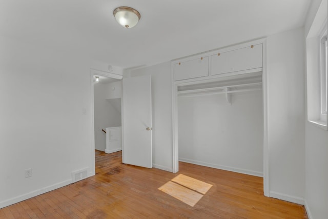 unfurnished bedroom with light wood finished floors, visible vents, baseboards, and a closet