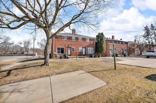 exterior space with a front yard, brick siding, and a chimney