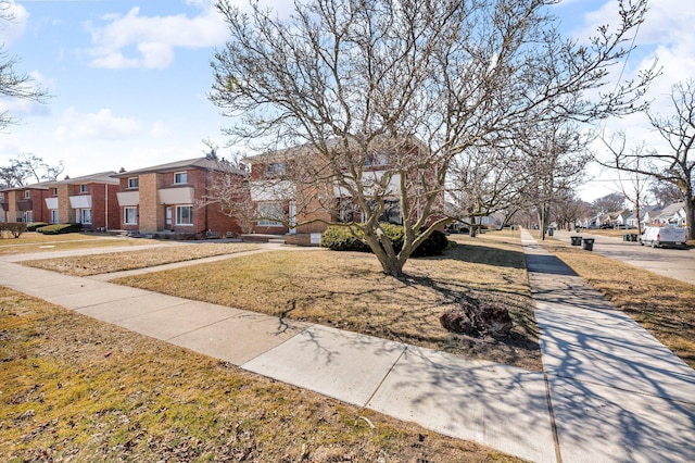 view of front of home featuring brick siding, a residential view, and a front yard