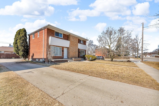 view of front of home with brick siding, a front yard, and fence