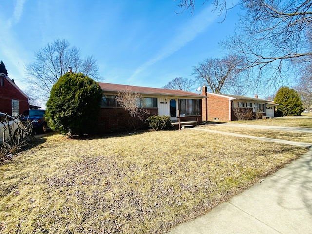 ranch-style house with a front yard, brick siding, and a chimney