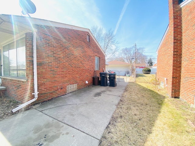 view of home's exterior featuring a detached garage, fence, and brick siding