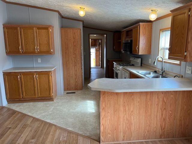 kitchen featuring a sink, stainless steel microwave, white gas range oven, light countertops, and lofted ceiling