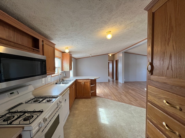 kitchen featuring stainless steel microwave, brown cabinets, white gas range, and a sink