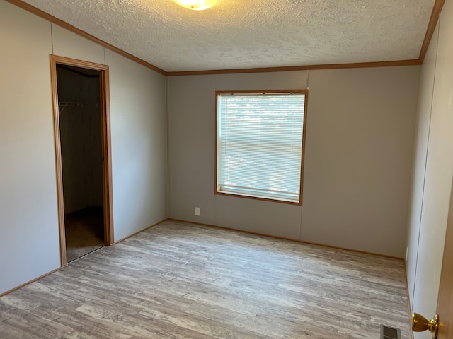 unfurnished bedroom featuring wood finished floors, visible vents, a closet, and ornamental molding