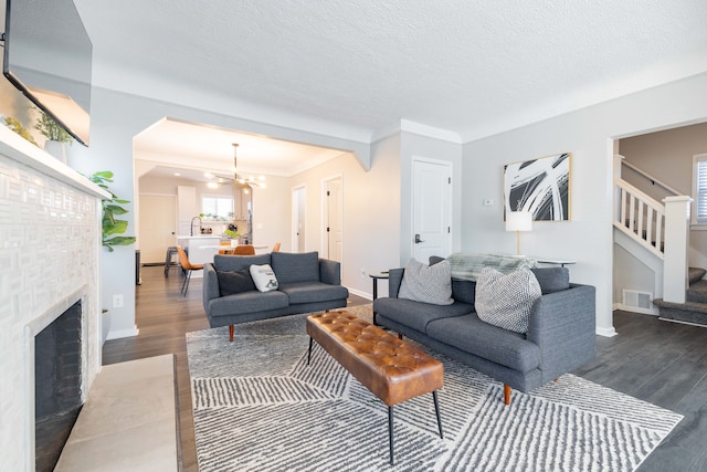 living room featuring dark wood finished floors, a notable chandelier, stairway, and visible vents