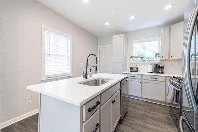 kitchen with a sink, tasteful backsplash, dark wood finished floors, appliances with stainless steel finishes, and light countertops