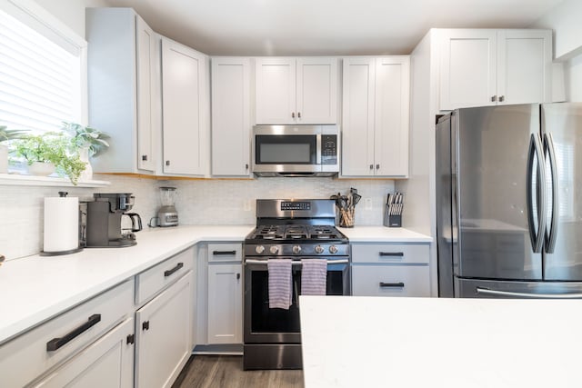 kitchen featuring light countertops, dark wood-style floors, tasteful backsplash, and stainless steel appliances