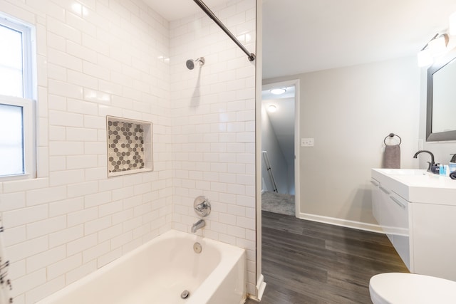 bathroom with toilet, wood finished floors, baseboards, bathing tub / shower combination, and vanity