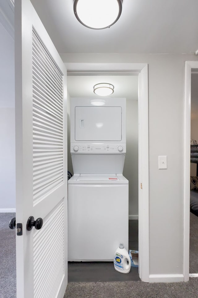 washroom featuring laundry area, stacked washer and dryer, carpet flooring, and baseboards