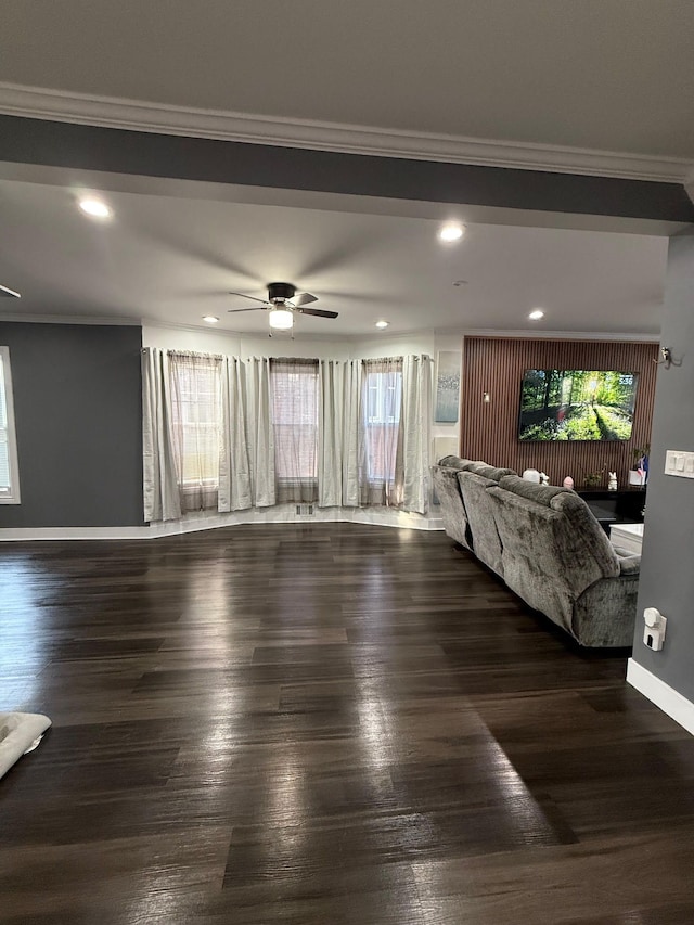 unfurnished living room with ornamental molding, baseboards, ceiling fan, and wood finished floors