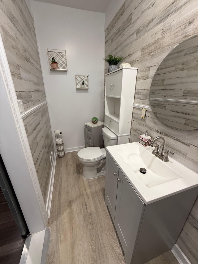 bathroom featuring vanity, wooden walls, toilet, and wood finished floors