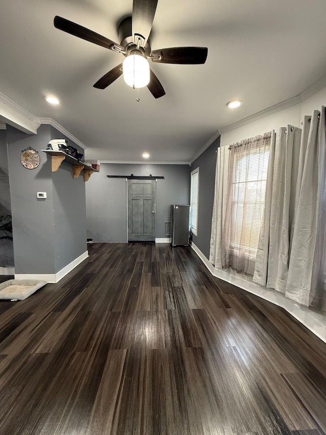 unfurnished living room featuring a barn door, crown molding, dark wood-type flooring, and baseboards