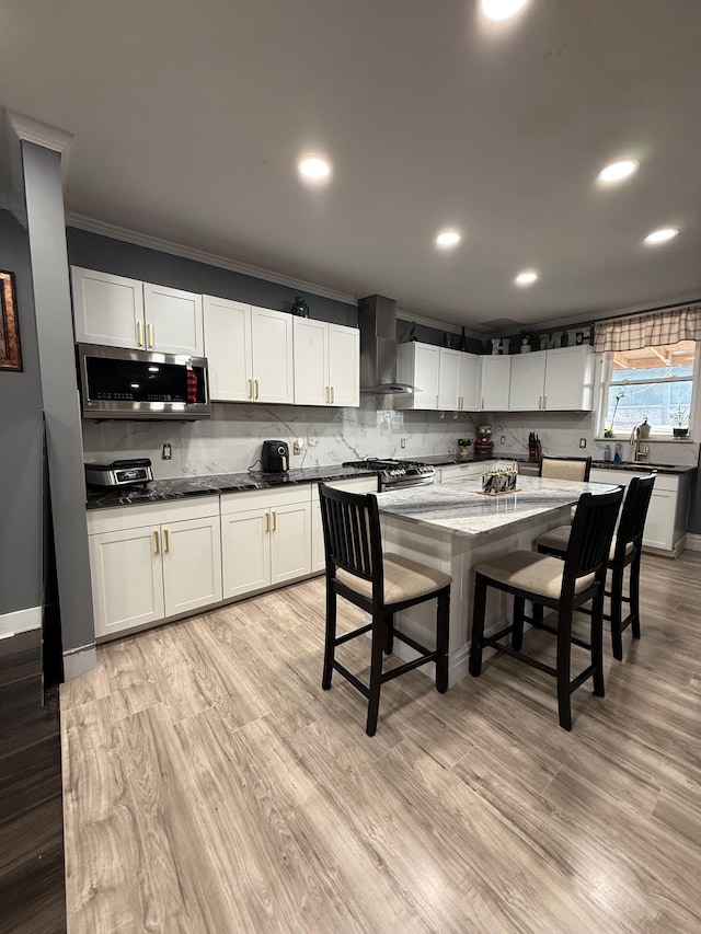 kitchen with wall chimney range hood, a breakfast bar area, backsplash, and stainless steel appliances