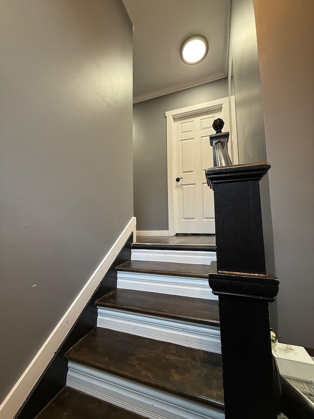 staircase with crown molding, baseboards, and wood finished floors