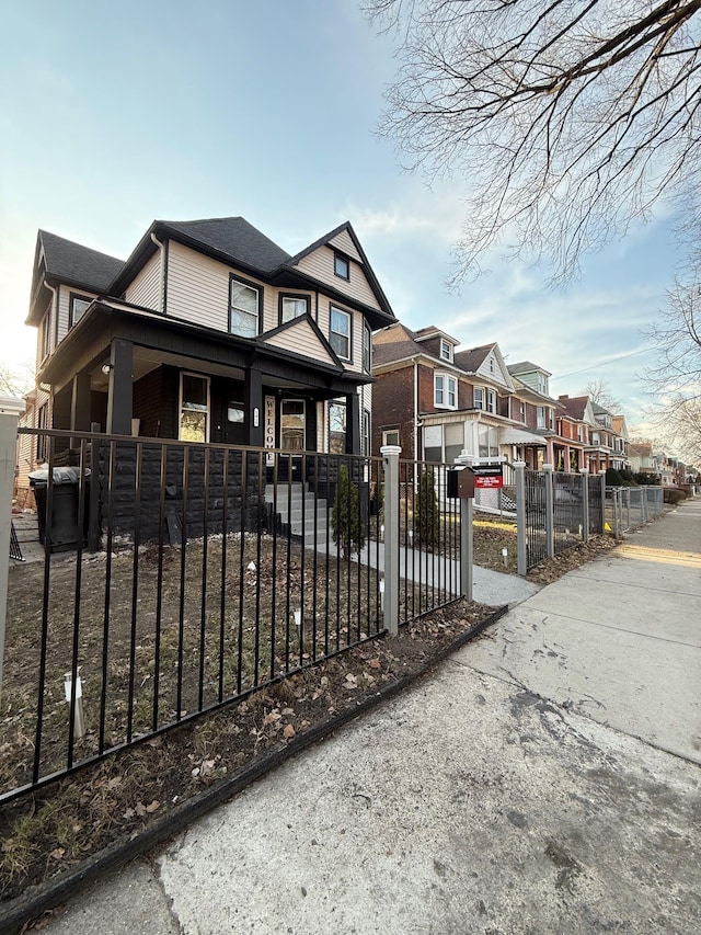 view of front of house featuring a porch, a residential view, and a fenced front yard