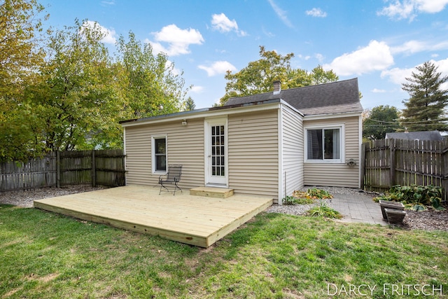 rear view of house with a chimney, a lawn, a wooden deck, and a fenced backyard