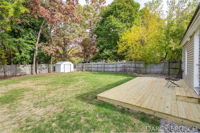 view of yard with a storage unit, an outbuilding, a wooden deck, and a fenced backyard