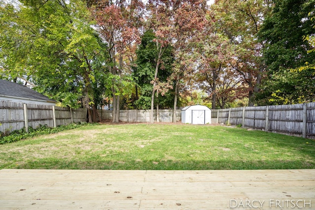 view of yard featuring a wooden deck, an outbuilding, a fenced backyard, and a storage shed