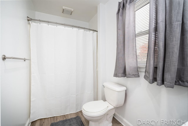 bathroom with toilet, a shower with shower curtain, baseboards, and wood finished floors