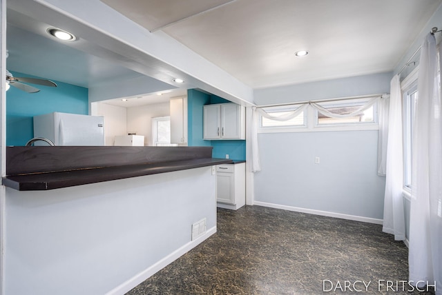 kitchen with dark countertops, visible vents, baseboards, recessed lighting, and freestanding refrigerator